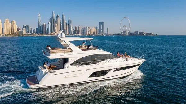 A 60 ft white motor yacht with a flybridge cruising off JBR, with Dubai Marina and Ain Dubai behind